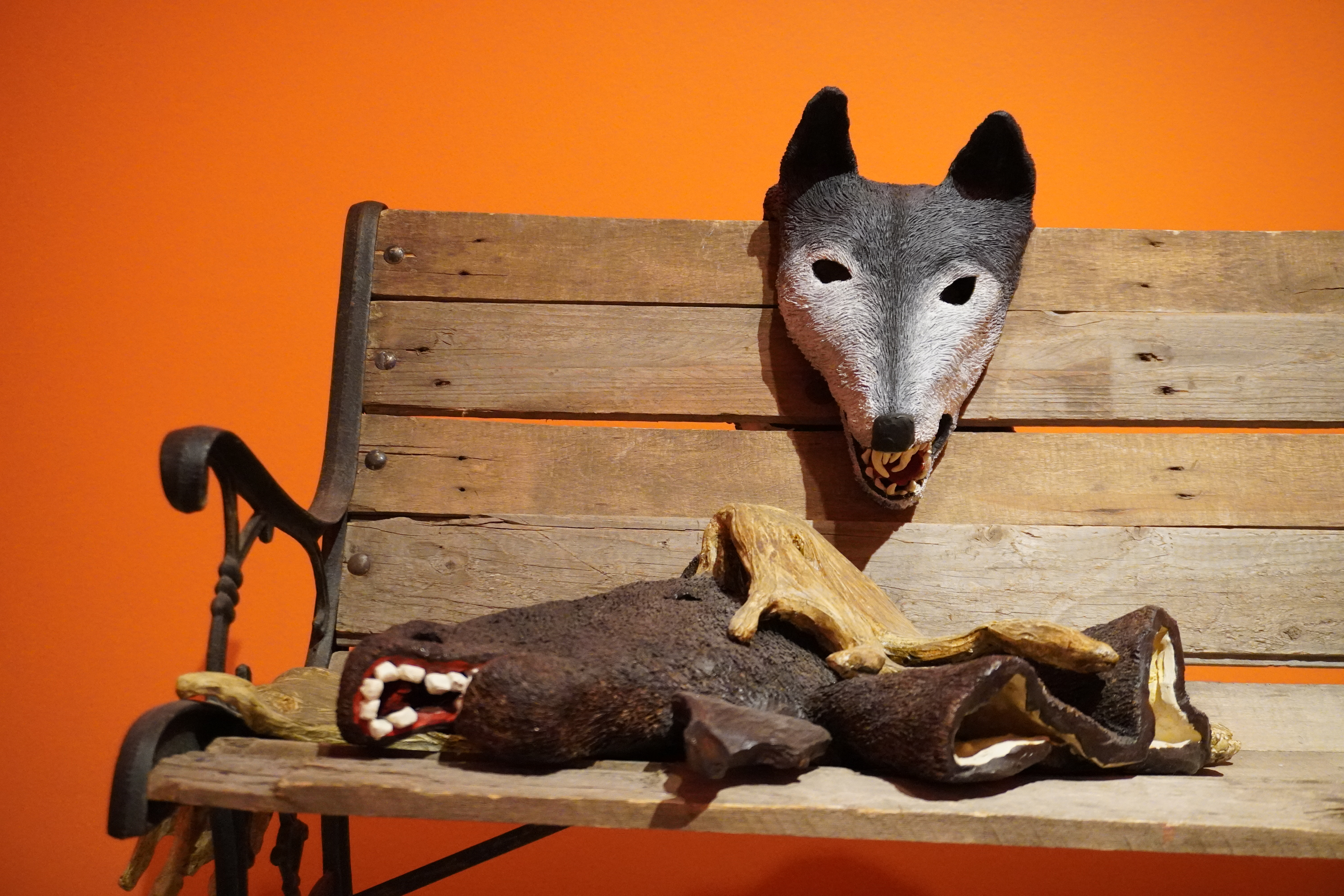 Creepy animal masks on a bench with a bright orange background.