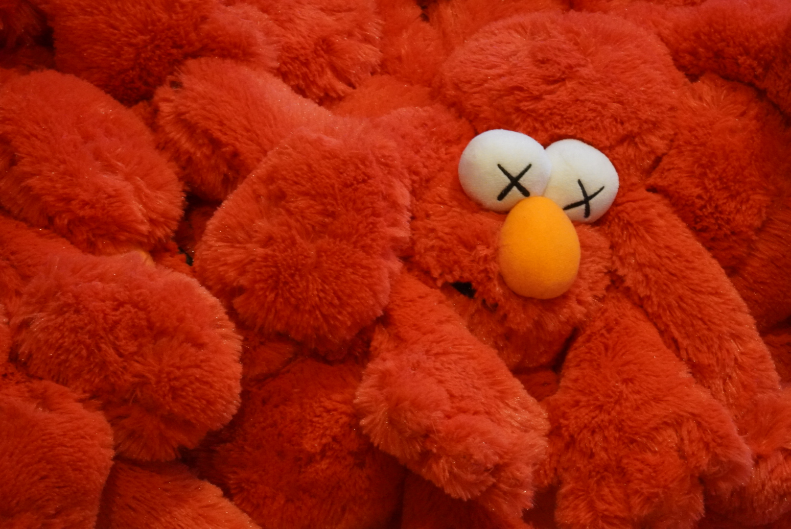 Elmo stuffed toy smothered amongst a pile of other Elmos.