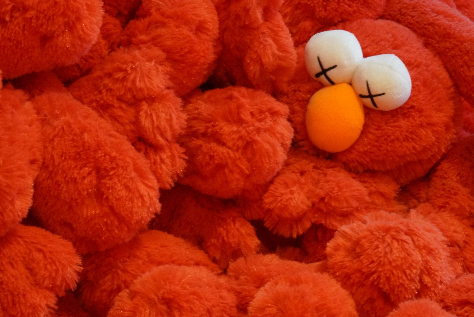 Elmo stuffed toy smothered amongst a pile of other Elmos.