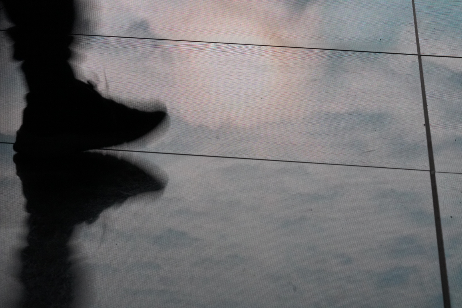 Foot in motion on glass surface in pastel lighting.
