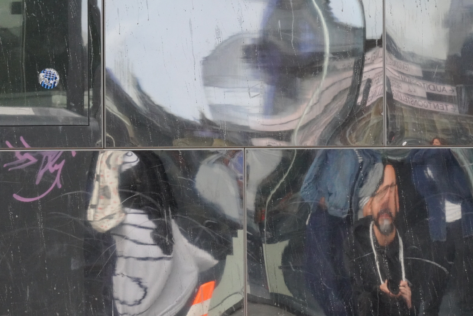 Photographer's reflection distorted in reflective glass.